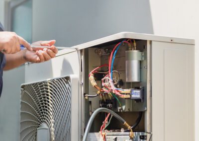 Technician repairing an air conditioning unit outdoors.